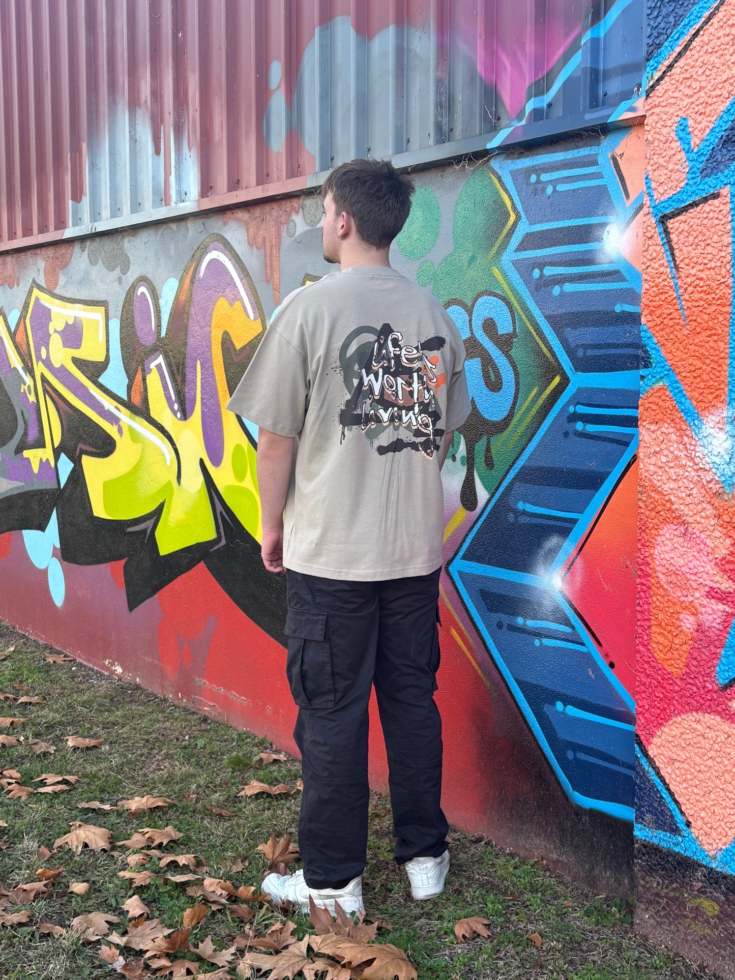 Person standing in front of a colorful graffiti wall in taggedstreetwear 