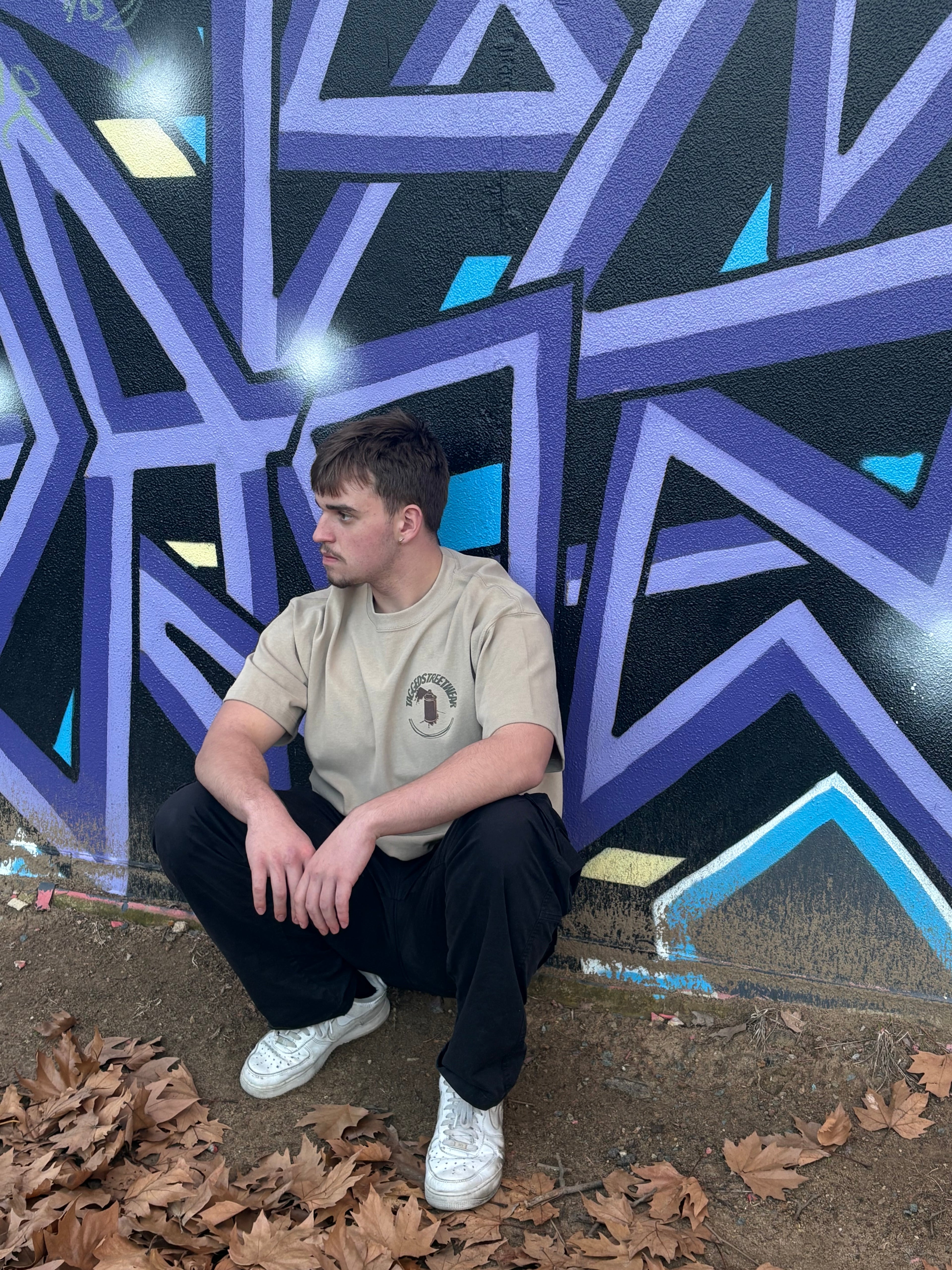 Person sitting in front of a geometric patterned in a taggedstreetwear tee